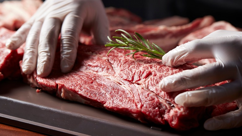 Raw meat being prepared with rosemary