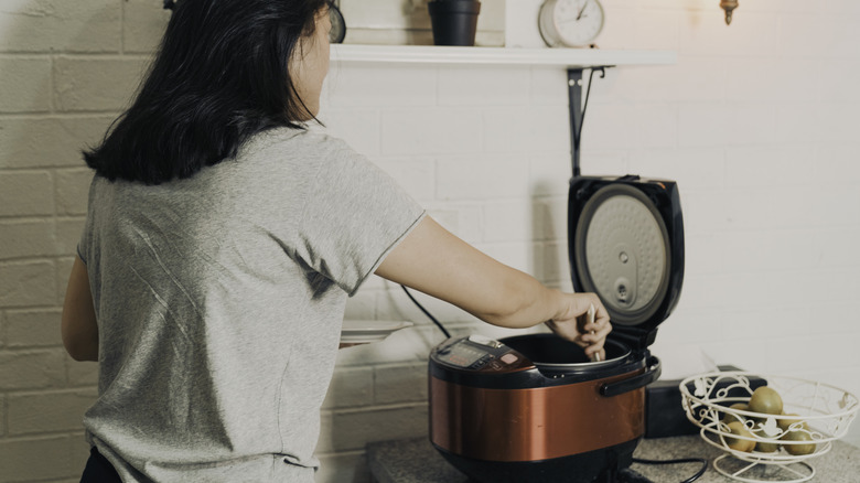 Woman preparing rice in a rice cooker.