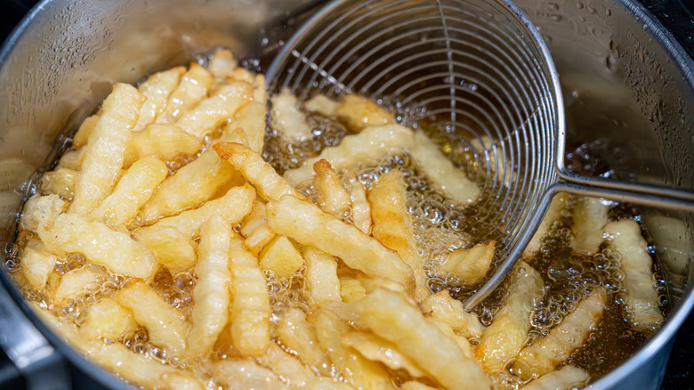 Strainer scooping fries in oil