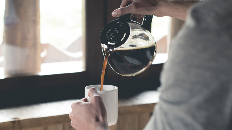 Pouring a cup of filter coffee by a bright window