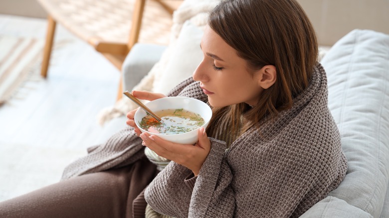 Sick woman drinking bowl of soup