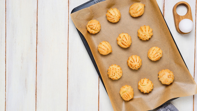 Freshly baked choux pastry profiteroles on a baking tray