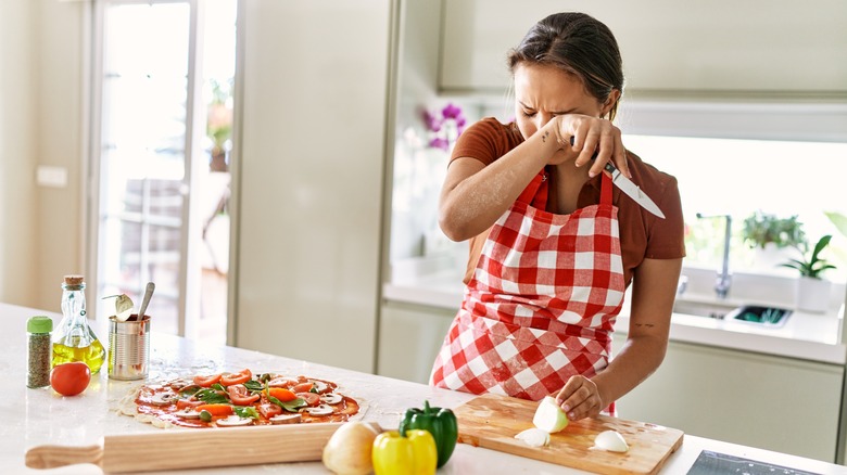 woman crying while cutting onions