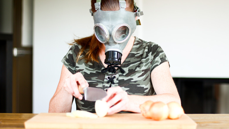 Woman wearing a gas mask while cutting onions