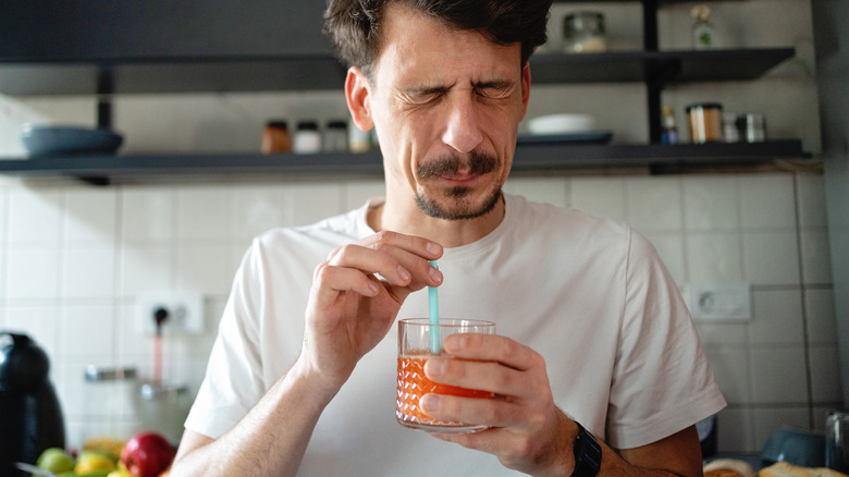 Man grimacing at a bitter taste from a drink