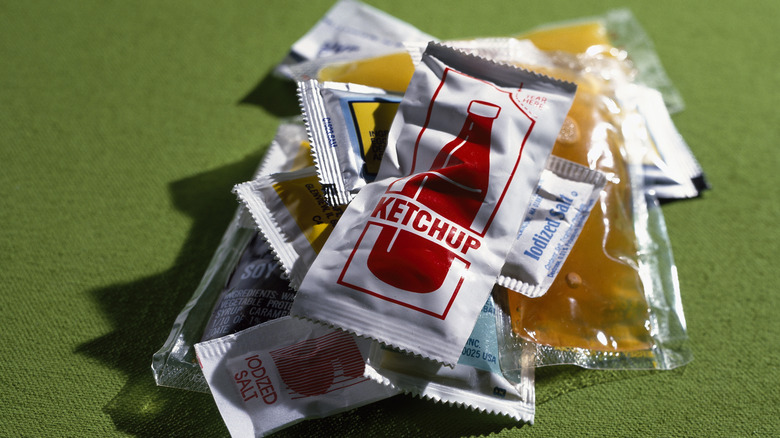 Condiment packets with ketchup on top of the pile