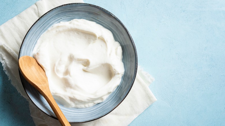 A bowl of sour cream with a spoon in it.