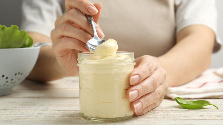 A woman holds a jar of mayo