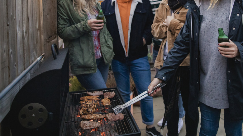 People in raincoats grilling