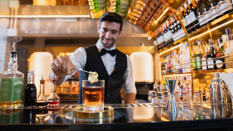 Bartender serving a whiskey cocktail