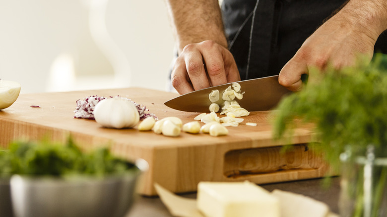 person chopping garlic on cutting board