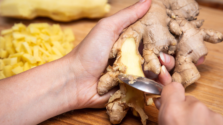 A woman peeling ginger with a spoon