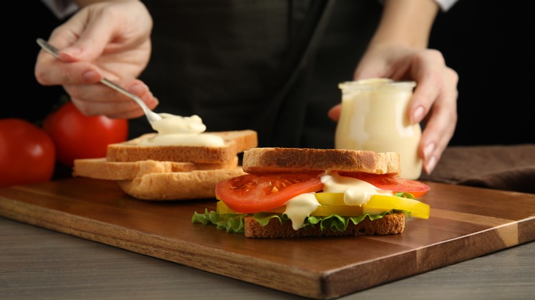 person spreading mayo on sliced bread