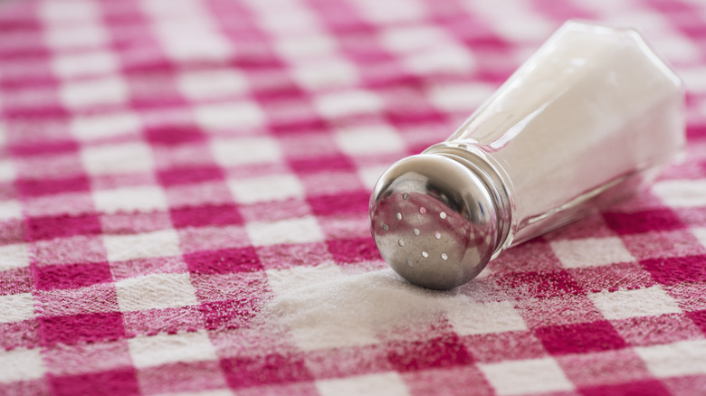 spilled salt shaker on gingham tablecloth