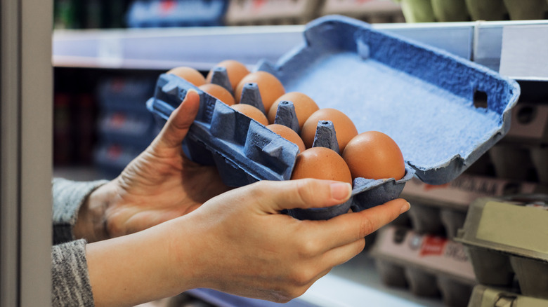 Person holding open blue carton of eggs