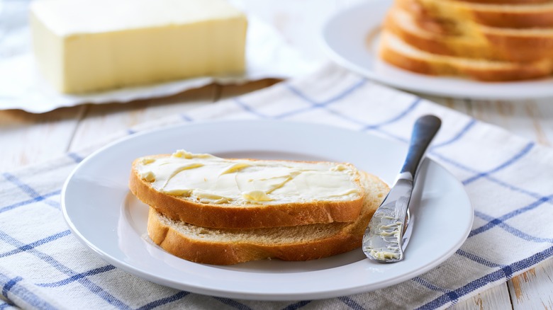 Piece of buttered white bread on a white plate