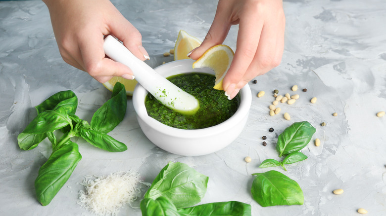 Woman adding lemon juice to pesto