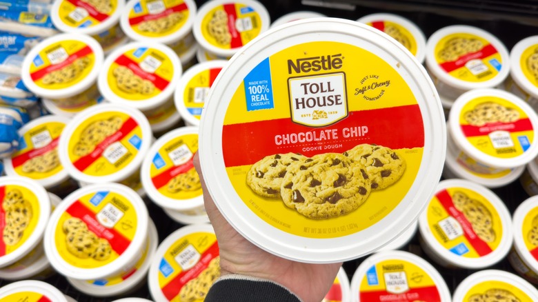 Hand holding tub of store-bought cookie dough