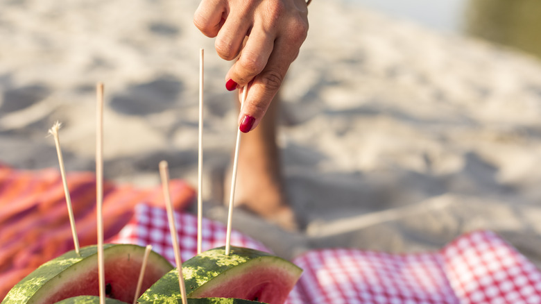 Person grabbing watermelon on a skewer