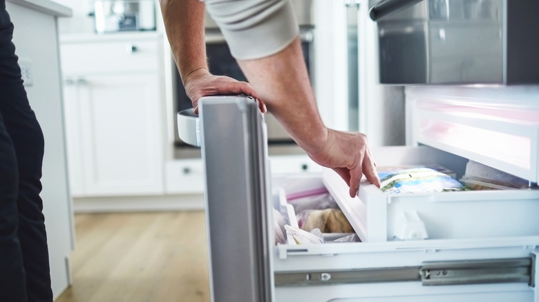 A person sifts through a home freezer drawer