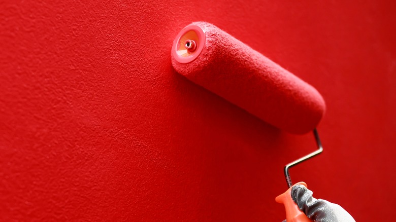 Hand painting a red wall with a roller