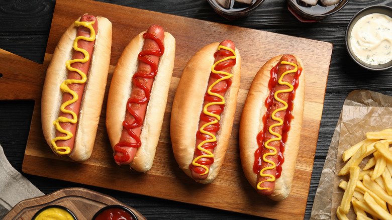 Four hot dogs topped with ketchup and mustard