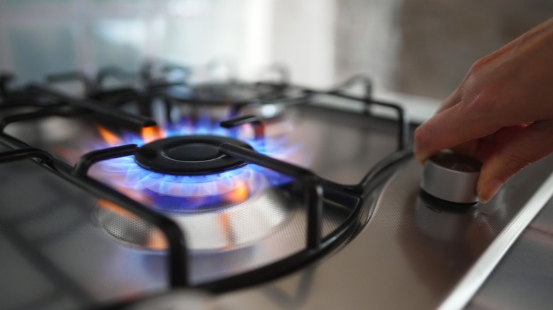 Hand adjusting the heat level of stove