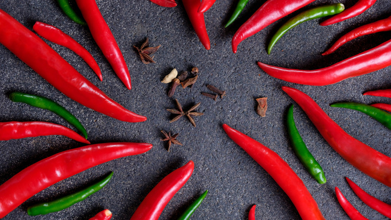 Arrangement of cloves, star anise, and red and green chili peppers.