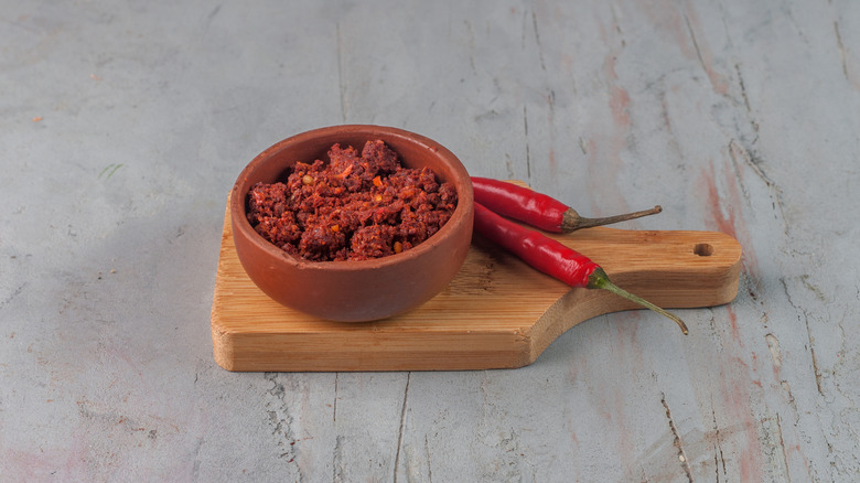 Harissa in a small bowl next to chile peppers