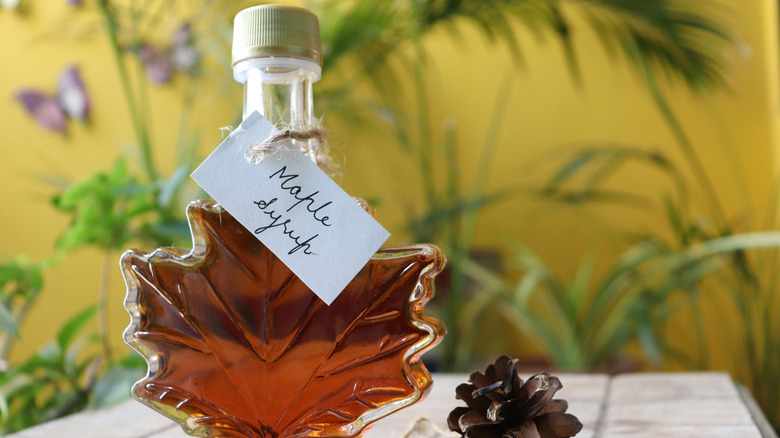 A leaf-shaped container of maple syrup with a hand-written label.