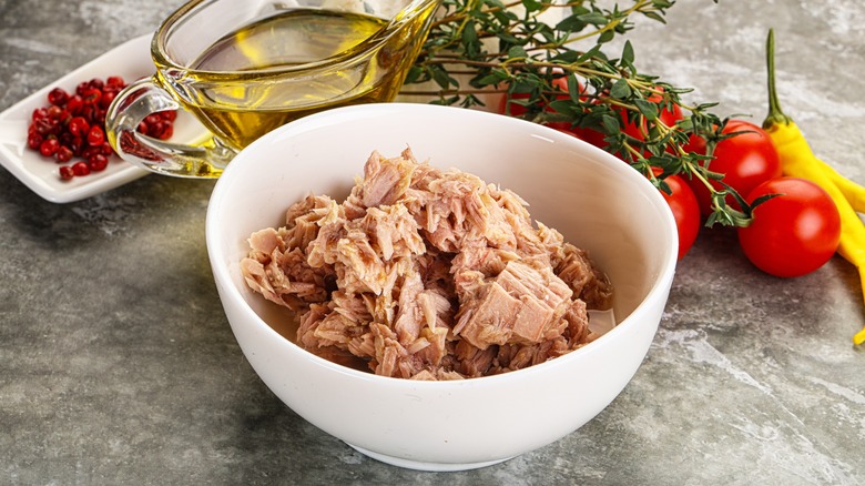 bowl of canned tuna surrounded by spices, herbs, vegetables