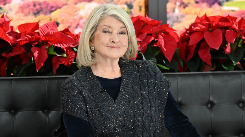 Martha Stewart smiles at an event in front of poinsettia