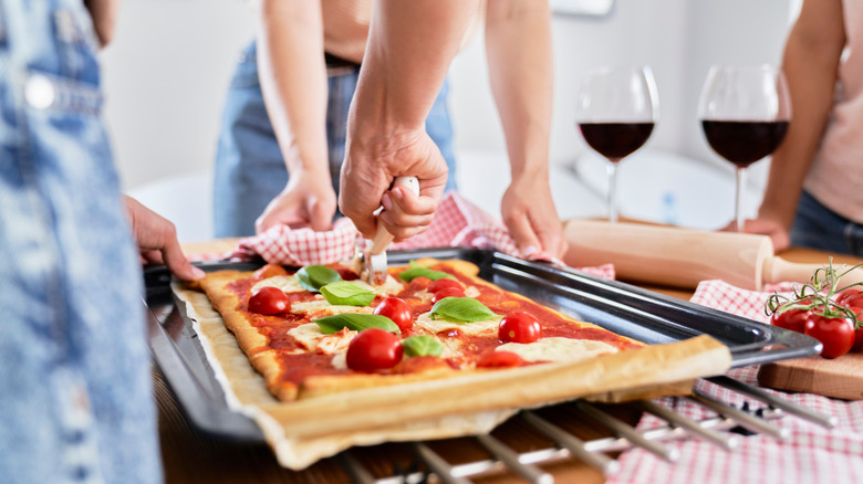 Person slicing store-bought pizza crust