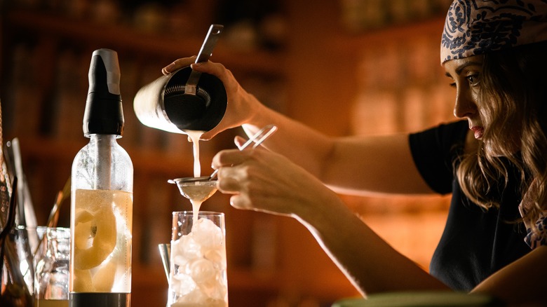 woman straining cocktail