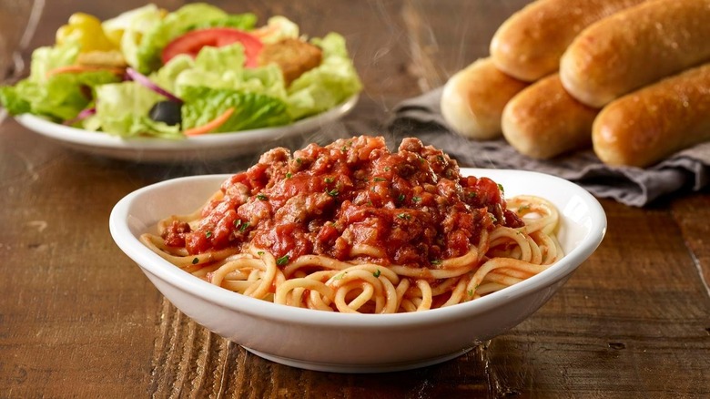 Dish of spaghetti with salad and breadstick