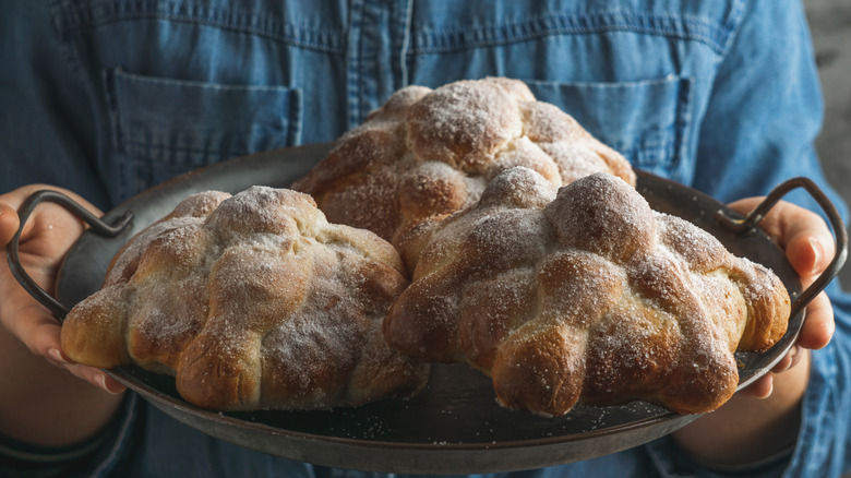 three pan de muertos dusted in sugar