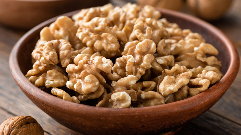 A wooden bowl of halved walnuts