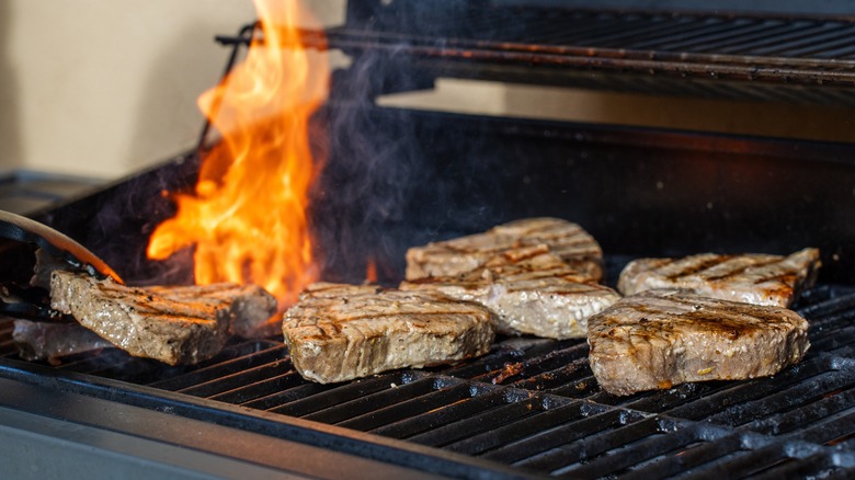 Numerous tuna steaks on a hot grill