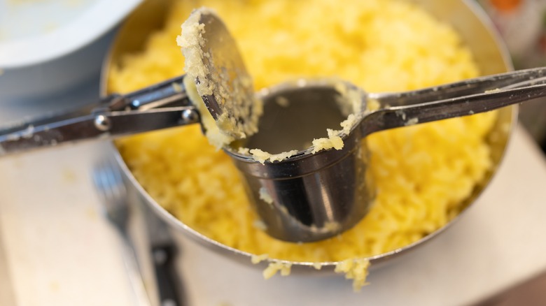 pressing potatoes through a potato ricer