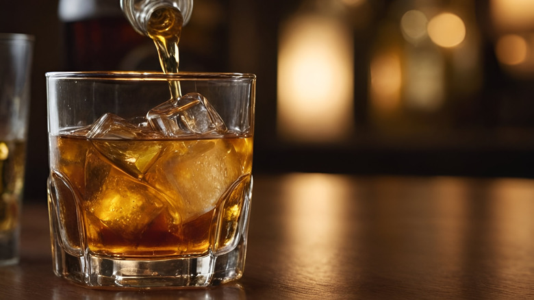 whisky being poured into a glass with ice