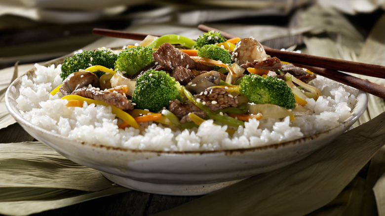 A bowl of beef and broccoli over rice