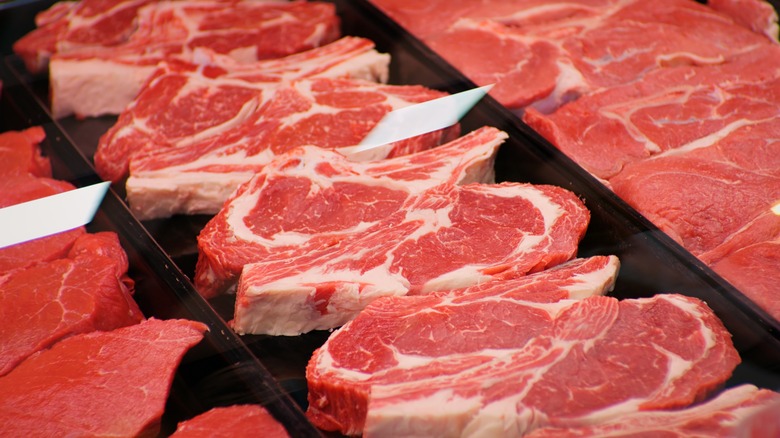 A line of ribeye steaks in a refrigerator cabinet.