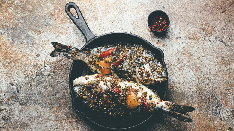 Two uncooked cod filets in a cast iron skillet