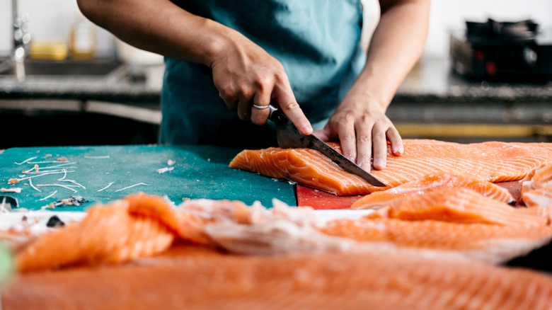 person slicing salmon on counter