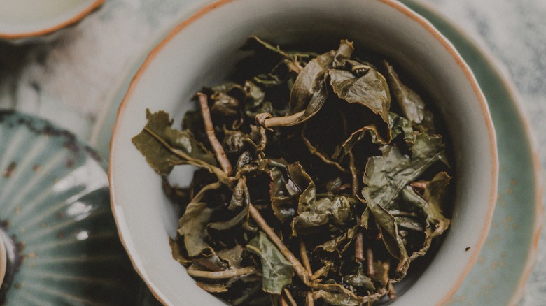 Dried tea leaves in a mug with saucer