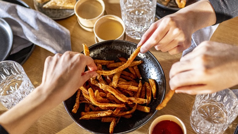 People sharing a bowl of Cajun-seasoned french fries