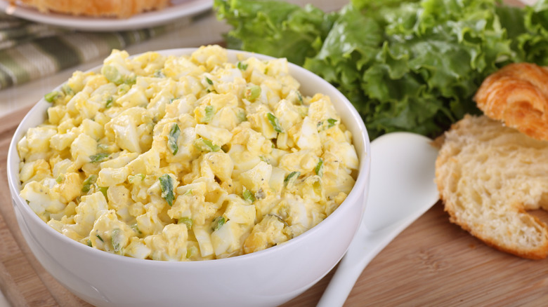 egg salad in a bowl with croissants and lettuce