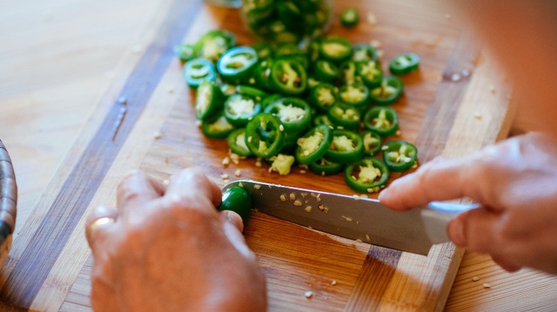 Hands slicing  jalapeños for pickling