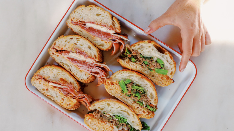 Hand reaching for platter of sandwiches