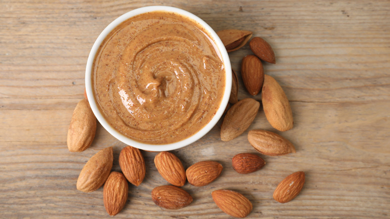 Aerial view of almonds surrounding a dish of almond butter